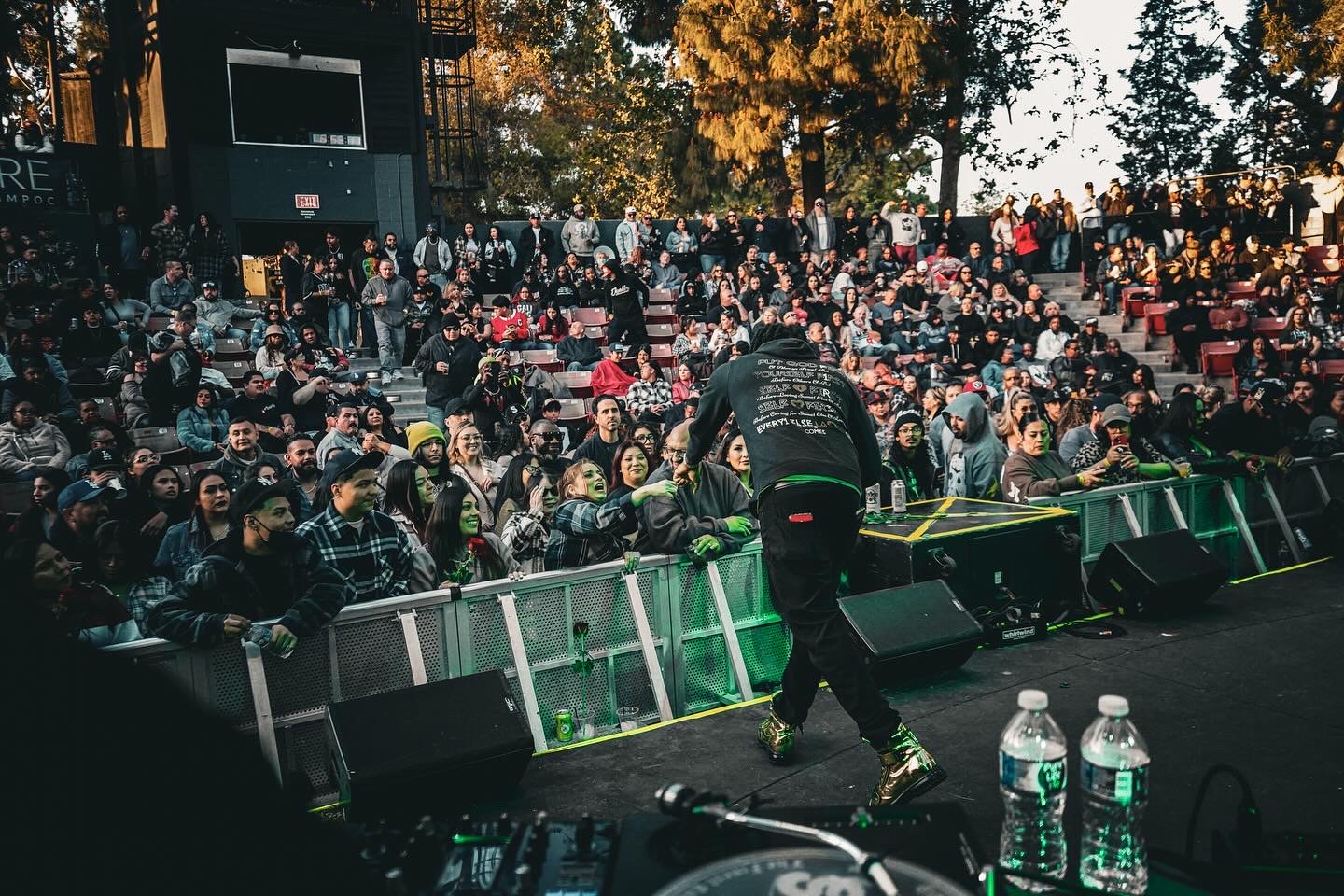 JoethePoet performing from the stage to a packed outdoor amphitheater